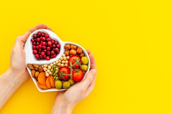Heart shaped food bowl filled with healthy snacks.